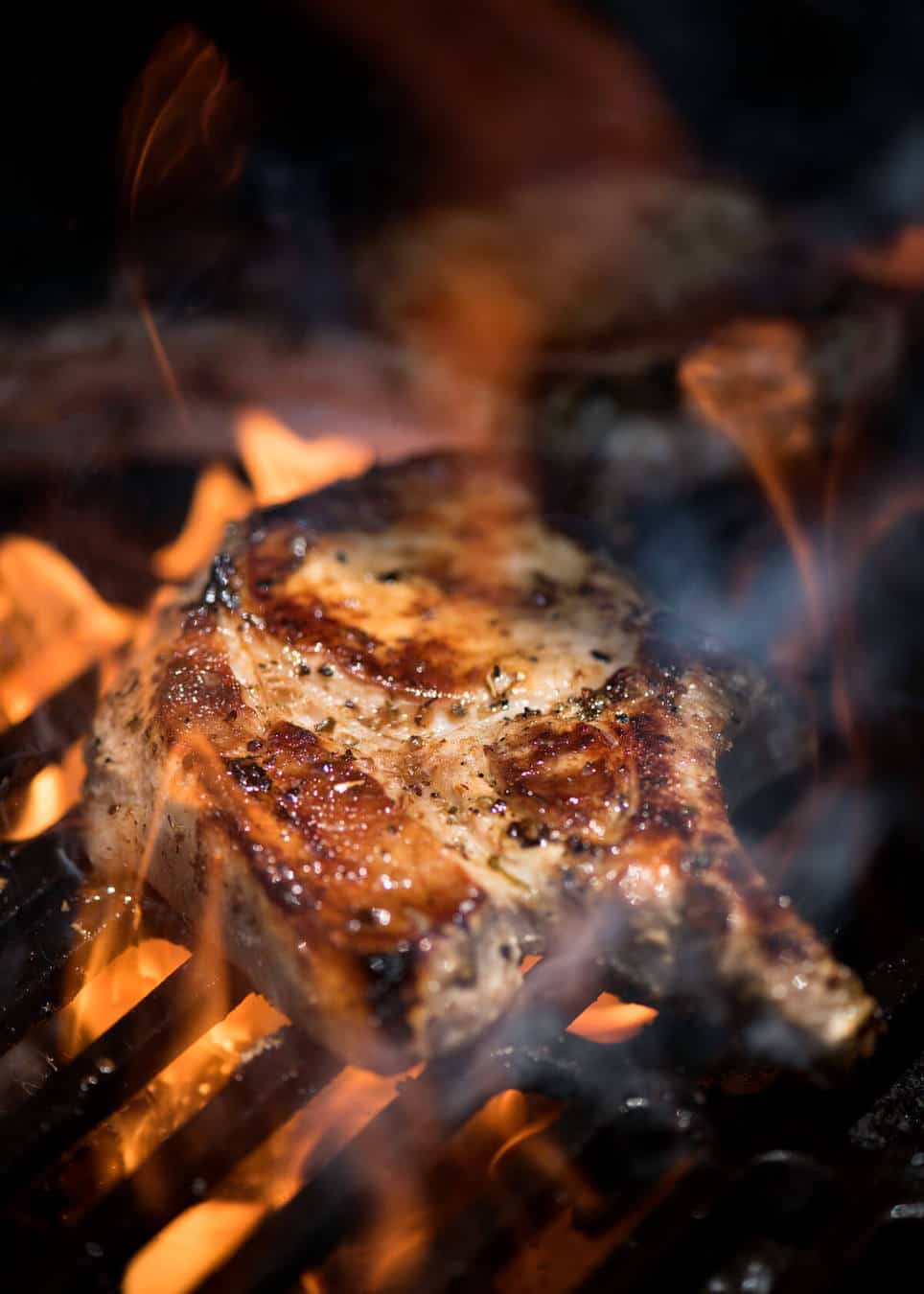 Lemon Garlic Marinated Grilled Pork Chops on the barbecue being licked by flames.