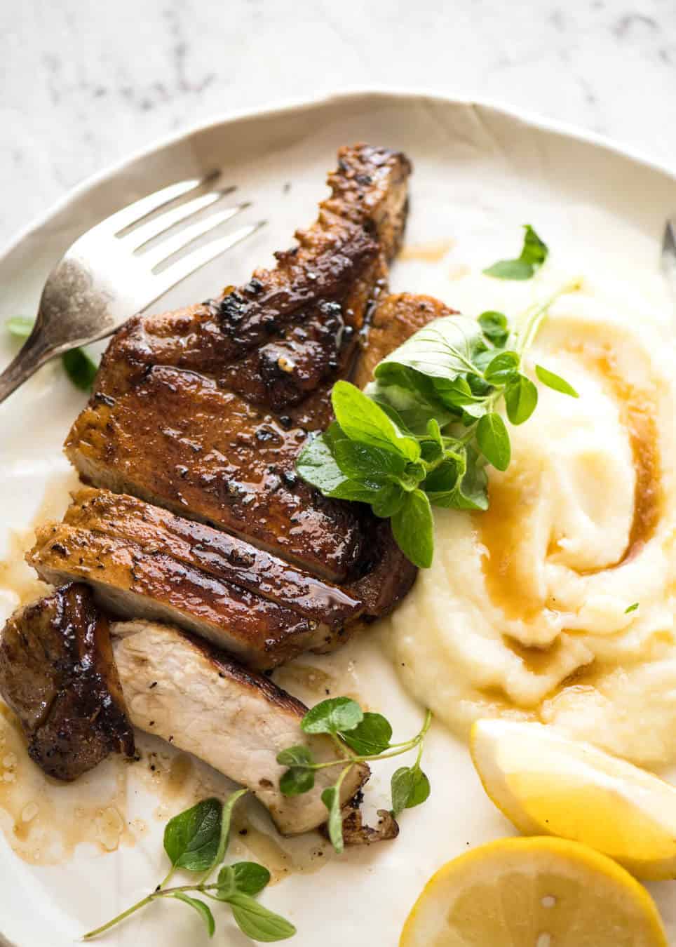 Lemon Garlic Marinated Grilled Pork Chops on a white plate with mashed potato on the side.